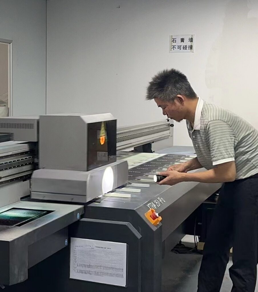 A worker holds a torch during the production of a timipick Pickleball paddle to check that the print on the surface of the paddle is up to standard